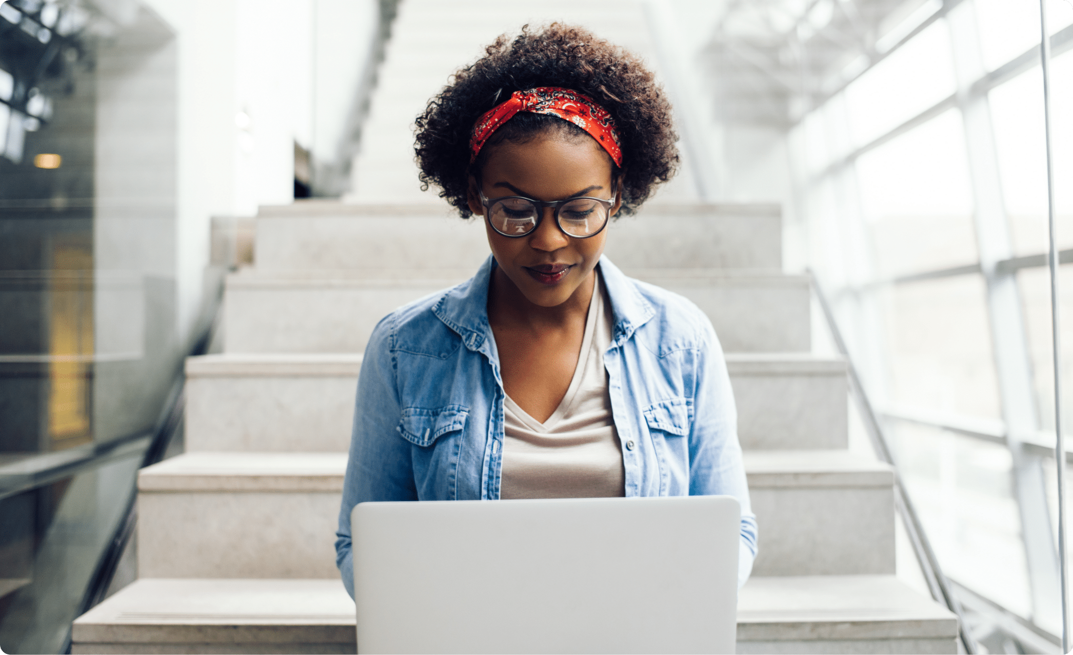 A woman working on her computer while sitting on some stairs