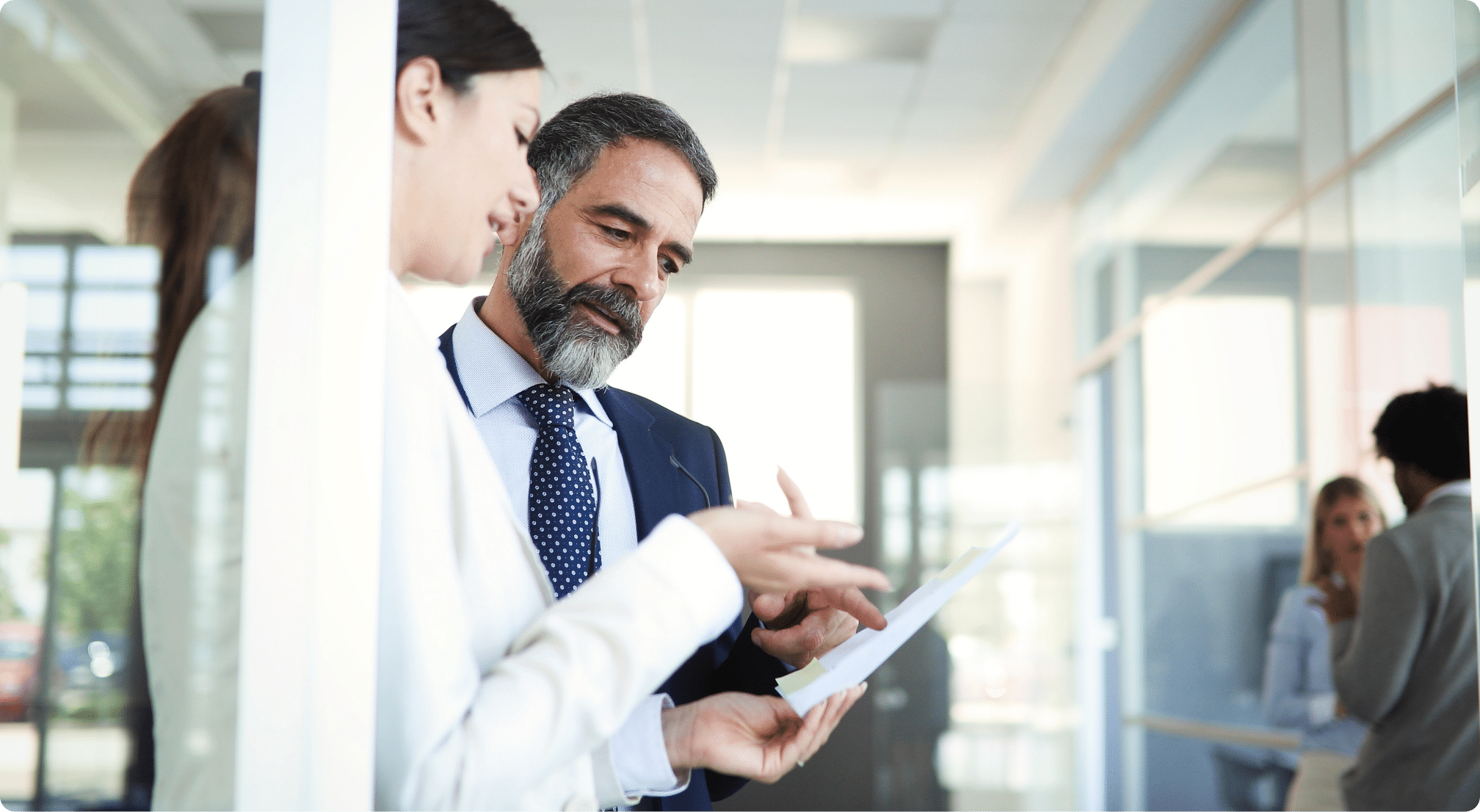 Two people discussing business ideals while pointing to a paper they both are looking at