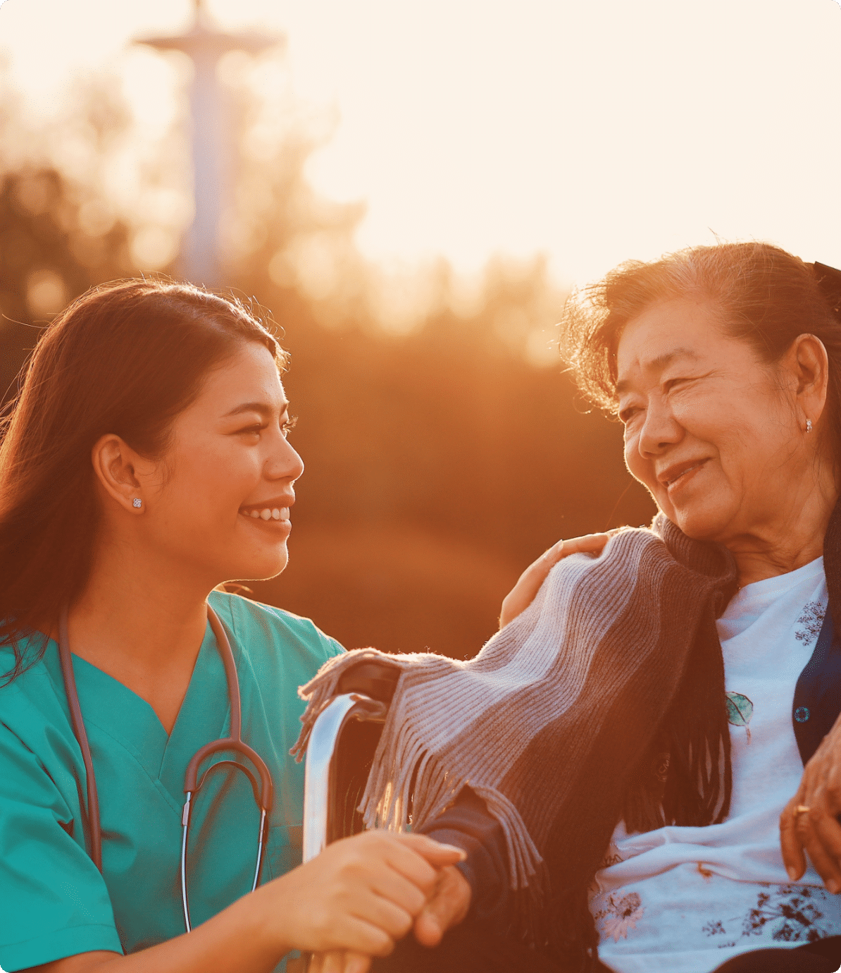 A woman nurse tending to an older woman with smiles on their faces